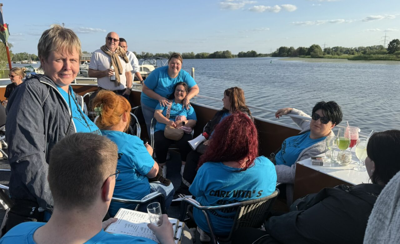 Personen auf dem Boot am sitzen am Tisch und einige stehen mit einem Getränk in der Hand