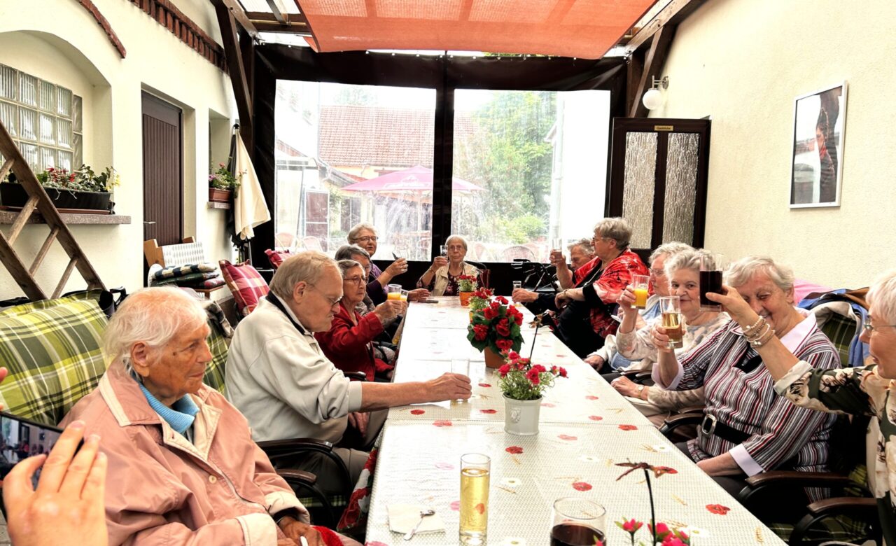 Mehrere ältere Menschen sitzen am Tisch und genießen die Getränke